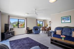 a living room with a blue couch and a tv at The Bowentown Bach - Waihi Beach Upstairs Unit in Katikati