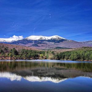 um reflexo de montanha num lago com montanhas cobertas de neve em Casa Pradillo 