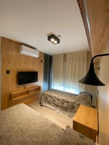 een slaapkamer met een bed en een flatscreen-tv bij TERMAS PISMANTA Hotel & Spa in Las Flores
