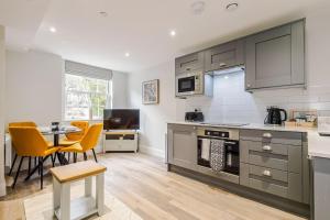 a kitchen with gray cabinets and a table and chairs at Rock Mill - 2-Bedroom Duplex Apartments in Stoney Middleton