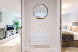 a white room with a bed and a mirror at Rock Mill - 2-Bedroom Duplex Apartments in Stoney Middleton