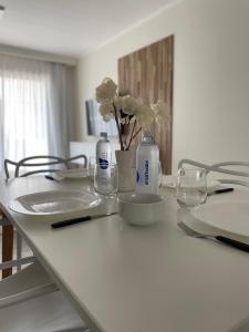 a white table with flowers and bottles on it at EN EL CENTRO DE LOBOS in Lobos