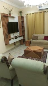 CORAL PLACE في Abeokuta: غرفة معيشة مع كنبتين وتلفزيون