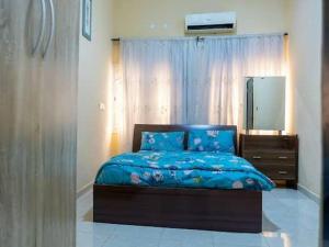 1 dormitorio con cama azul, tocador y espejo en CORAL PLACE, en Abeokuta