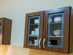 CORAL PLACE في Abeokuta: خزانة مع بابين زجاجيين مع أطباق فيها
