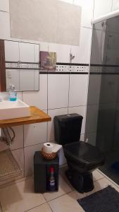 Łazienka z czarną toaletą i umywalką w obiekcie Casa aconchegante térrea à 3min de carro do centro e praia central w mieście Garopaba