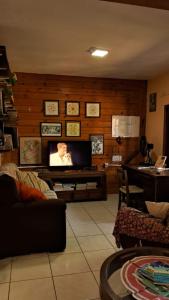 uma sala de estar com uma televisão de ecrã plano na parede em Casa aconchegante térrea à 3min de carro do centro e praia central em Garopaba