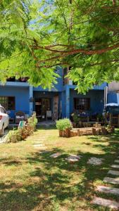 ein blaues Gebäude mit einem Baum davor in der Unterkunft Casa aconchegante térrea à 3min de carro do centro e praia central in Garopaba