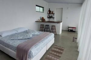 a bedroom with a bed and a kitchen with stools at Bem Vindo Ao Presente in Igrejinha