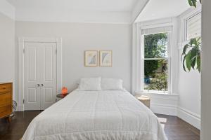 een witte slaapkamer met een bed en een raam bij Minimalistic 1885 Queen Anne Cottage 2B-2B Upper Level Flat in Alameda in Alameda