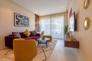 a living room with a purple couch and yellow chairs at Appartement luxueux et lumineux Maarif Casablanca in Casablanca