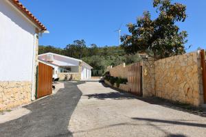 una strada con un muro di pietra e una recinzione di Da Serra guesthouse a Porto de Mós