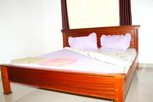 Cama de madera con sábanas y almohadas blancas en AUTOP BG Guest House en Kigali