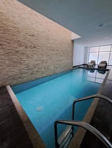 a large swimming pool in a building with chairs at Luxury Suite Wifi & Pool in Guayaquil