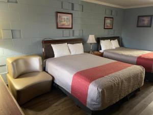 a hotel room with two beds and a chair at Safari Motel in Nephi