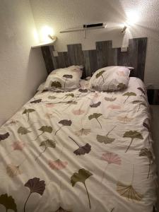 ein Bett mit einer Decke mit Blättern drauf in der Unterkunft T2 village naturiste Aphrodite in Leucate