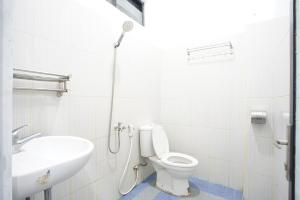a bathroom with a white toilet and a sink at Hotel Bhakti in Padang