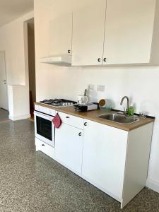 - une cuisine blanche avec évier et cuisinière dans l'établissement Lucilio - intero appartamento, à Rome