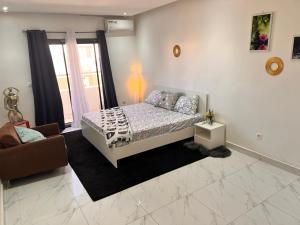 a bedroom with a bed and a chair and a window at LUXE Appartement in Dakar
