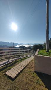 a bench next to a fence with the sun in the sky at Chalés Ninho do Poeta in Gonçalves