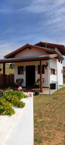 ein kleines weißes Haus mit einer Veranda und ein paar Blumen in der Unterkunft Chalés Ninho do Poeta in Gonçalves