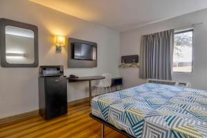 um quarto de hotel com uma cama, uma secretária e uma televisão em Motel 6 Little Rock AR South em Little Rock