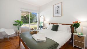a bedroom with a bed and a table and a chair at Wollumboola Lake House in Culburra Beach