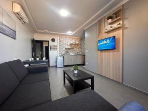 a living room with a couch and a tv on a wall at Hotel Cataleya Al-Hoceima in Al Hoceïma