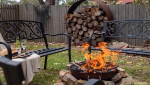 a fire pit in a yard with a bunch of logs at Wollumboola Lake House in Culburra Beach
