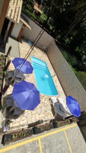 a swimming pool with three blue umbrellas and a swimming pool at Pousada Flor do Campo Cipó in Santana do Riacho