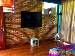 a room with a brick wall with a flat screen tv at Casa completa próxima a Ouro Preto! Amarantina in Ouro Preto