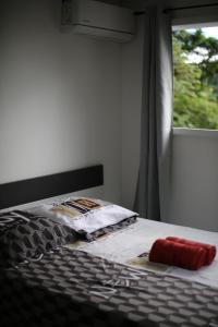 a bed with a red pillow and a window at Villa les MAHOGANYS in Rivière-Salée