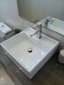 y baño con lavabo blanco y espejo. en Casa Premium em Balneário Gaivota, en Sombrio