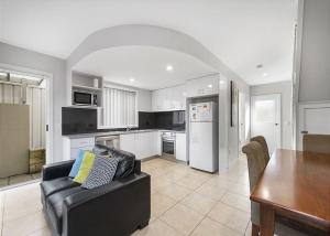 a living room with a black couch and a kitchen at Adrift, 5B Scott Street in Crescent Head