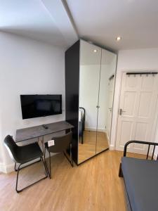 a room with a desk and a tv and a mirror at Lovely one bedroom garden flat in Hendon in The Hyde
