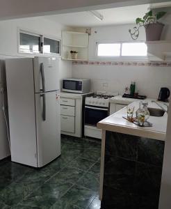 Il comprend une cuisine équipée d'appareils électroménagers blancs et d'un réfrigérateur blanc. dans l'établissement AppartMaipu496, à Balcarce