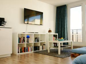 a living room with a tv and a white book shelf at Alpenblick in Sankt Englmar