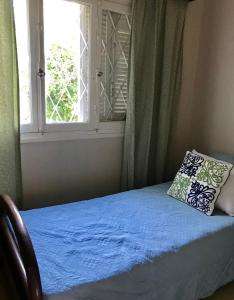 een bed met een blauw laken en een raam bij Hostel Casa Don Vicente in Mendoza