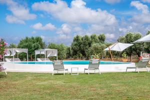 un gruppo di sedie e ombrelloni di fronte alla piscina di Villa Clive Relax & Sun a Ostuni