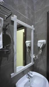 baño con espejo y lavabo en شهرزاد للأجنحة الفندقية, en Abū Qa‘ar