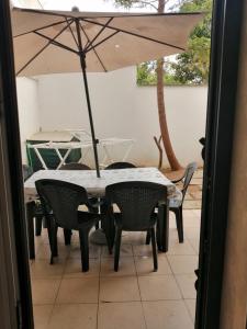 - une table et des chaises avec un parasol sur la terrasse dans l'établissement Case in Residence Torre dell'Orso, à Torre dell'Orso