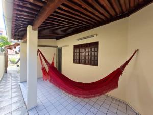 amaca rossa appesa sul lato di un edificio di Casa agradável: piscina, churrasqueira e redário. a Natal