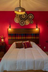 een slaapkamer met een groot wit bed en een rode muur bij DEPARTAMENTO DE LUJO AJIJIC in Jocotepec