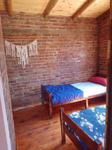 um quarto com duas camas e uma parede de tijolos em Cabaña arcoiris em El Parador