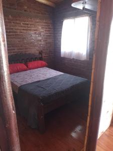 um quarto com uma cama e uma parede de tijolos em Cabaña arcoiris em El Parador