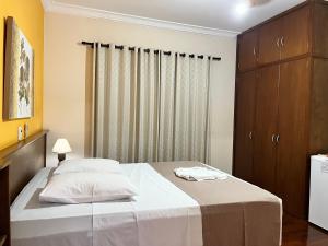 um quarto com uma cama com lençóis brancos e uma janela em Hotel São Marcos em Orlândia