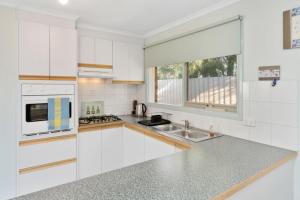 a white kitchen with a sink and a microwave at Bay Beach Beauty in Blairgowrie