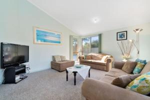 a living room with two couches and a tv at Bay Beach Beauty in Blairgowrie
