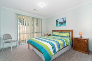 a bedroom with a bed and a chair and a window at Bay Beach Beauty in Blairgowrie