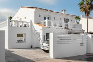 ein weißes Haus mit einem Auto in der Einfahrt in der Unterkunft Tooker Villa De La Playa La Cala de Mijas in La Cala de Mijas